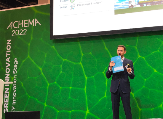 man presenting on a stage holding a paper