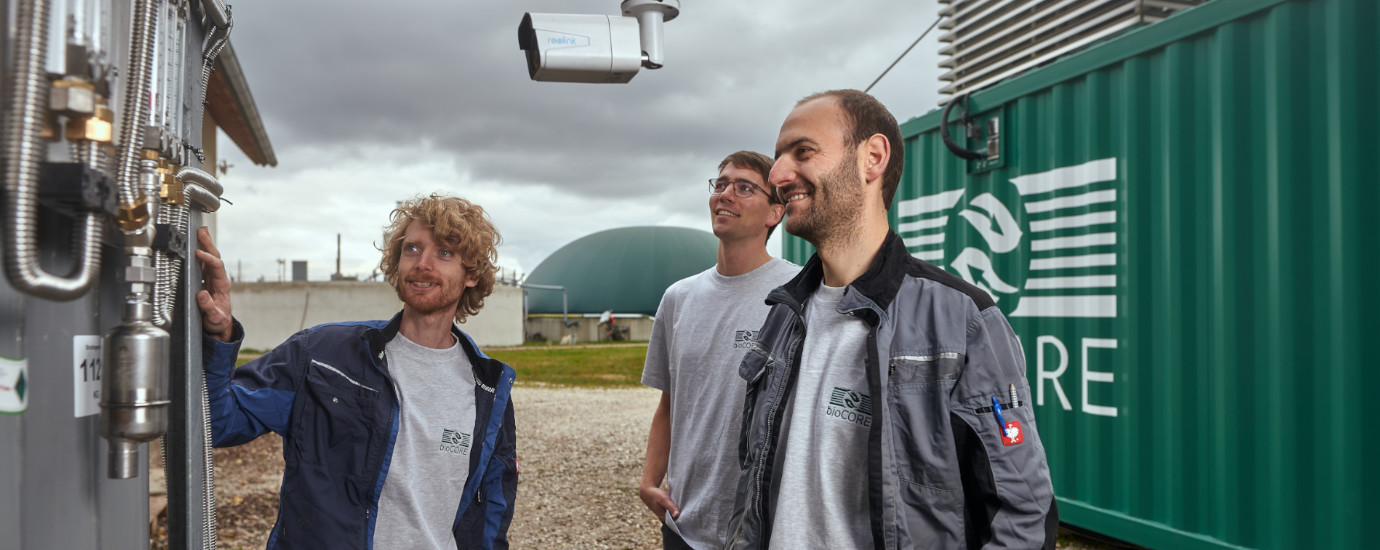 three smiling men looking at pipes.