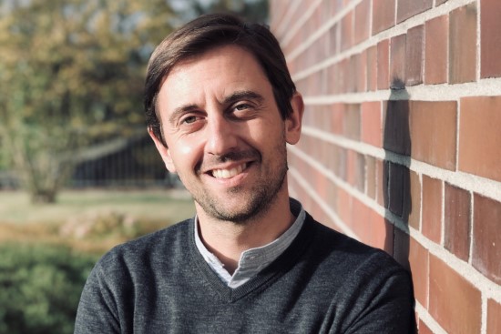 a man leaning on a wall smiling towards the camera