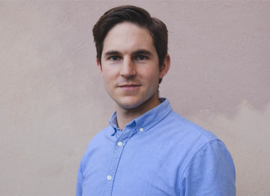 portrait of a man with dark hair and a blue shirt.