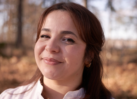 Woman with long brown hair smiling into camera