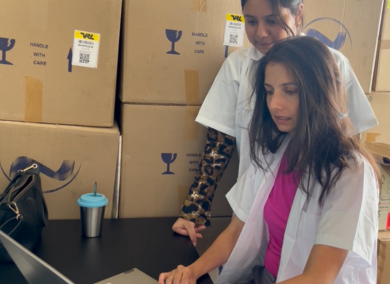 Two indian women before a laptop in a package filled room